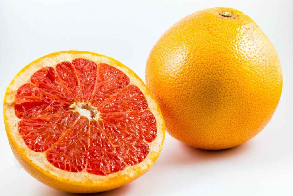 How is CBD like grapefruit? Both could interact with some pharmaceutical drugs. Photo shows two grapefruits, one whole and one sliced in half to show the inside. 