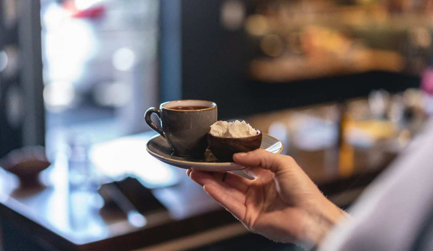 A barista serves coffee with a side of fresh whipped cream in Portland's elegant GrönCafe, a dedicated CBD cafe.