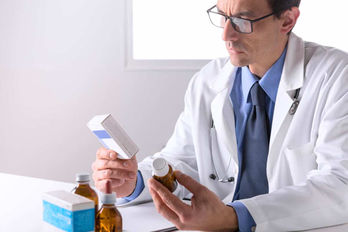A pharmacist in a lab coat examines bottles of medicine. Though research is only in its preliminary stages, doctors and pharmacists could someday prescribe cannabinoid antibiotics to their patients.