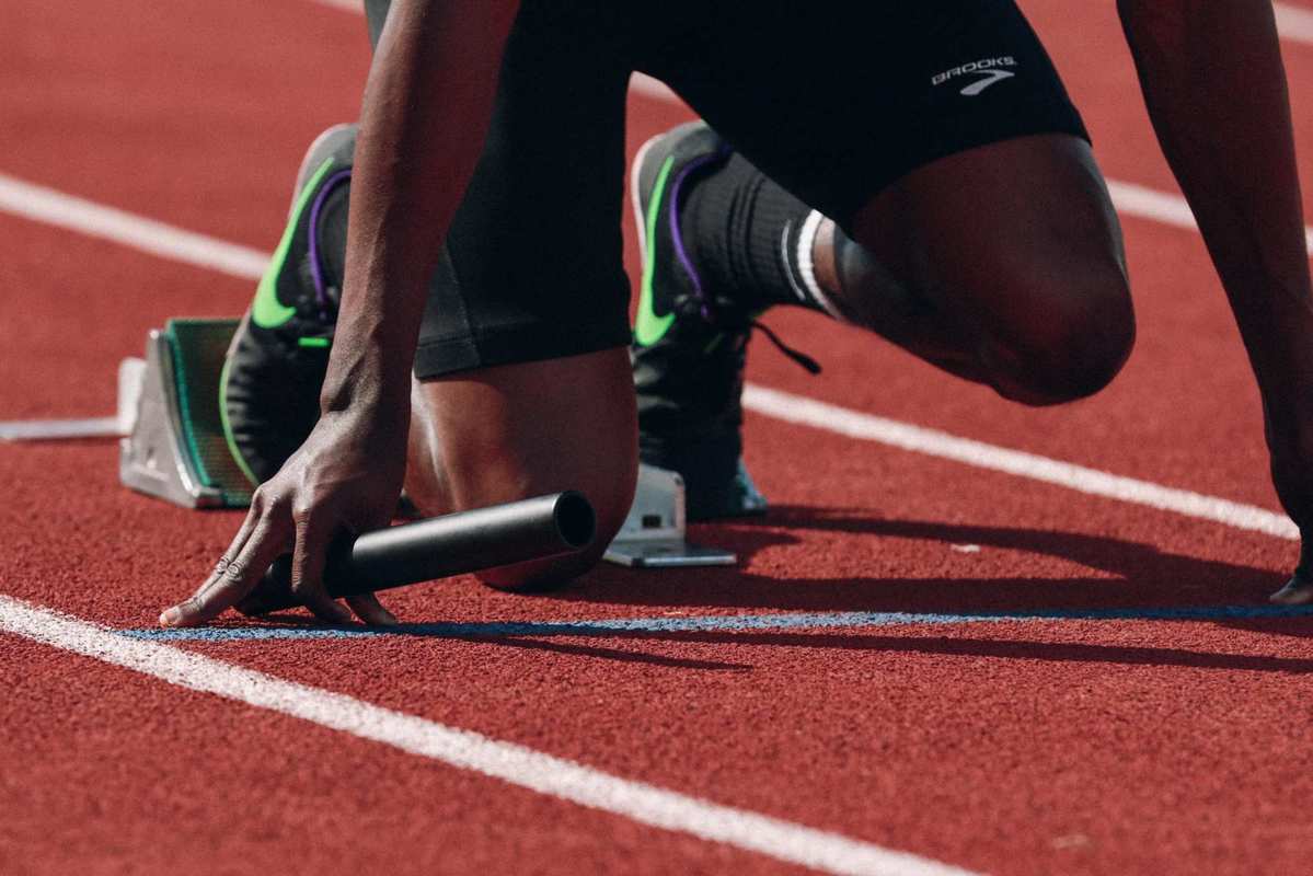 A runner is crouched on the starting line, ready to race on a track. Using CBD oil can actually boost stamina, which is just one of several benefits of working out with CBD.