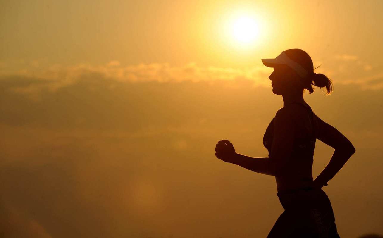A silhouette of a runner jogging during a sunrise. Distance runners, triathletes, professional cyclists and other endurance athletes use CBD because it helps them perform better and longer.