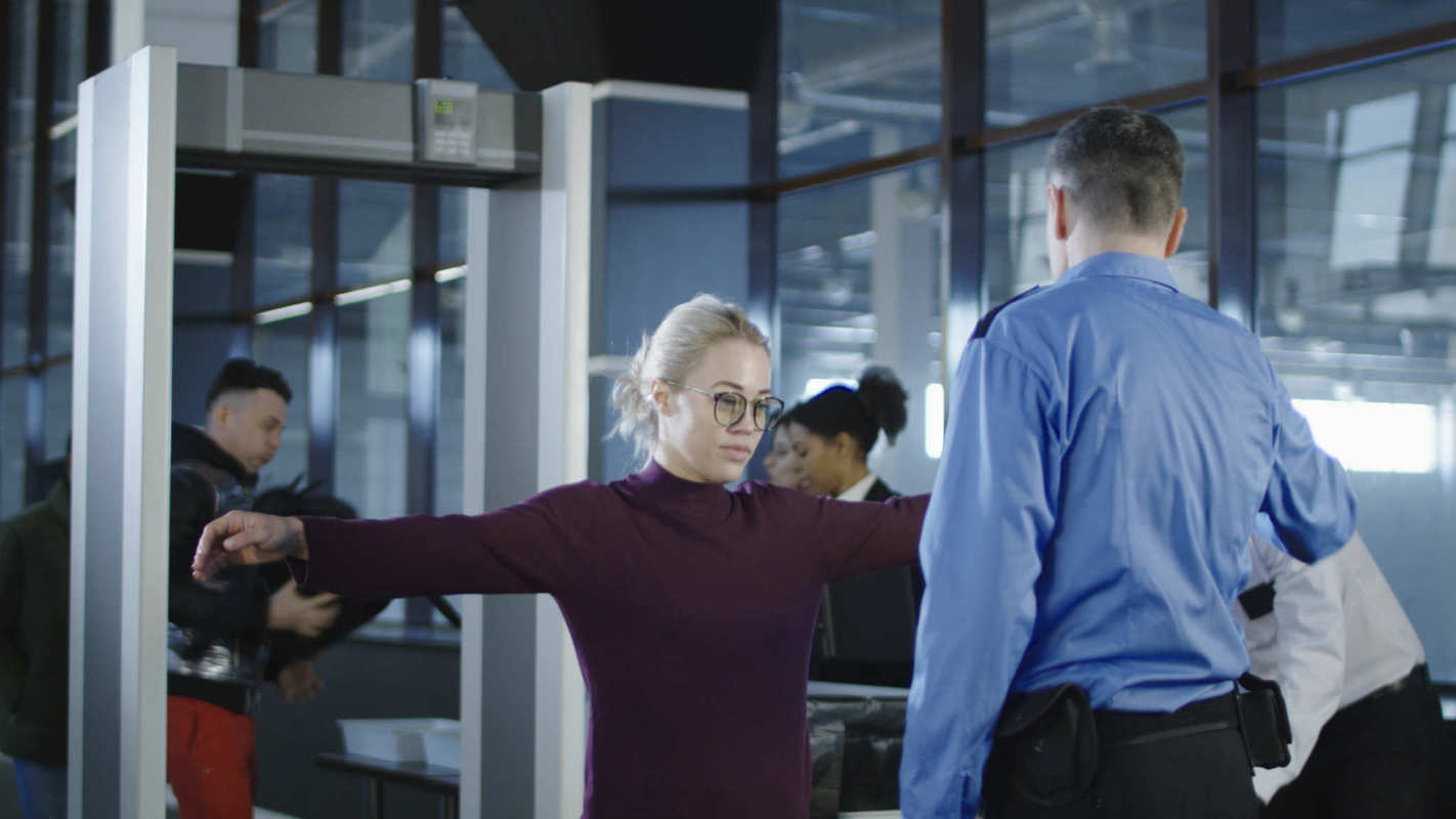 When bringing CBD through airport security, you may need to place it with other small liquids in a ziplock bag, under the TSA's "3-1-1 rule." Photo: A woman holds out her arms during a TSA security check before flying.