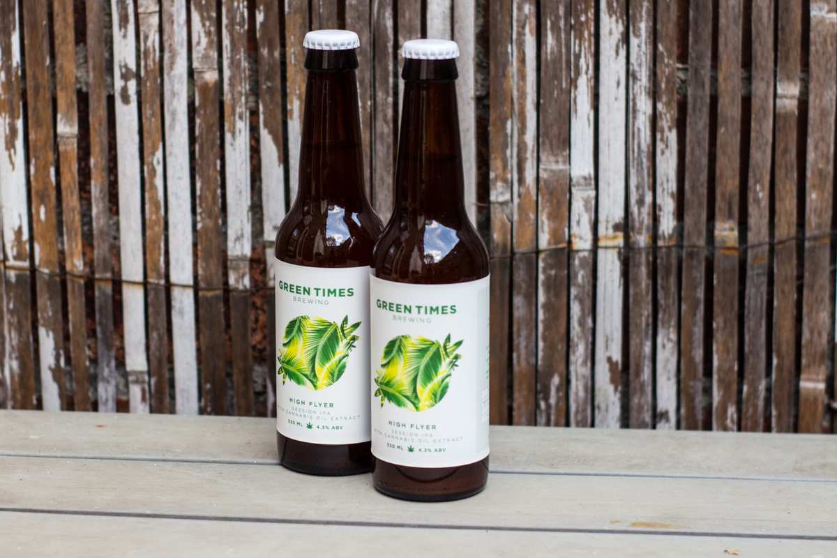 Two bottles of "High Flyer" CBD Beer sit on a table in front of a worn bamboo backdrop. Brief initial setbacks led the team behind "High Flyer," a unique CBD beer, to develop a better product including a fully organic formula.