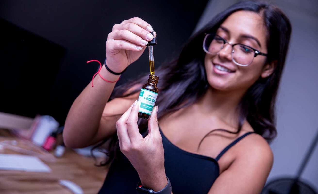 A woman smiles as she takes a dropper of Medix CBD Oil. Medix CBD combines pure CBD isolate with nourishing hemp seed oil.