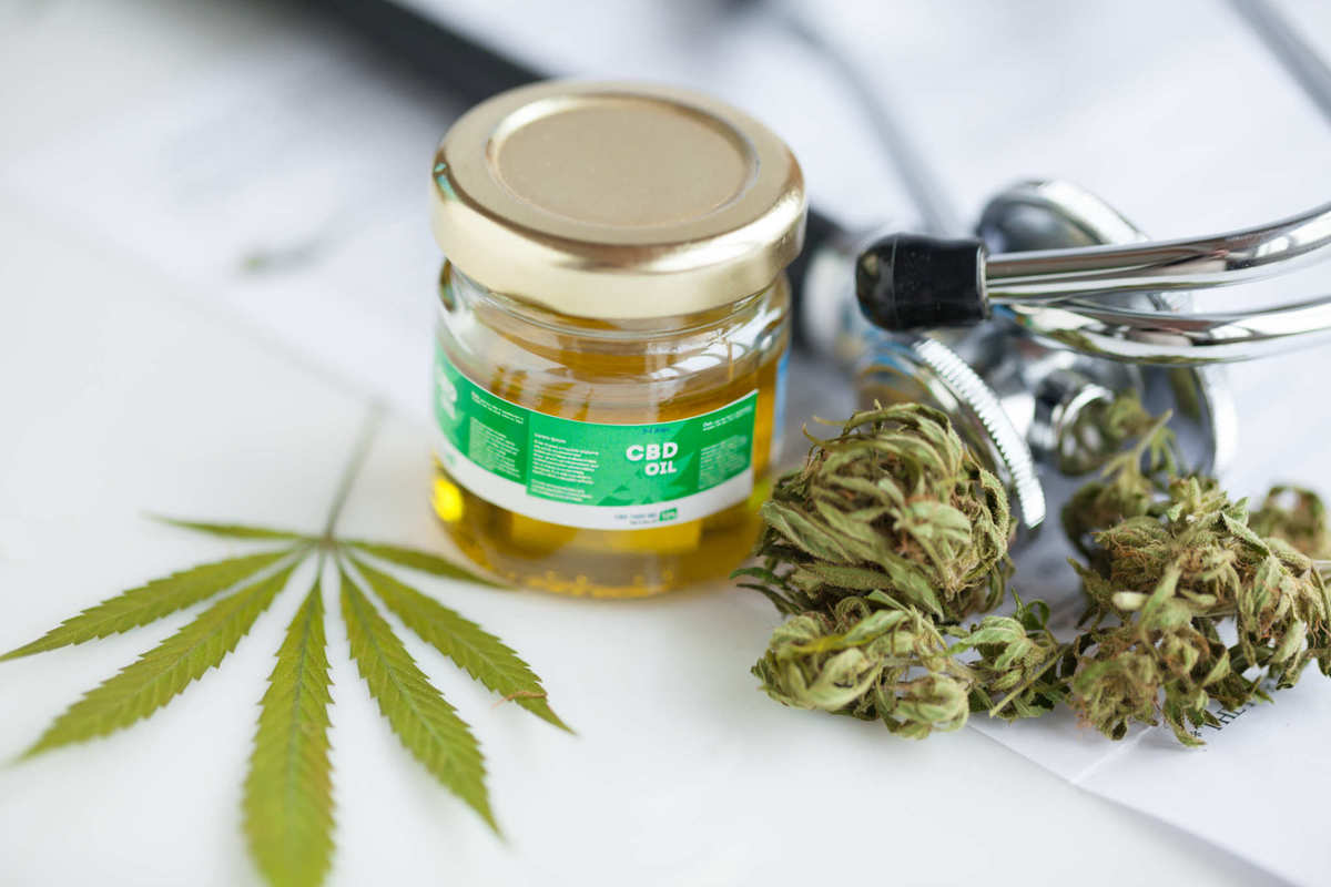 A stethoscope rests near a hemp leaf, some hemp flower buds, and a jar of CBD oil. Although CBD is widely recognized as safe, many medical professionals are still reluctant to recommend it. Patients are often forced to research CBD for themselves.