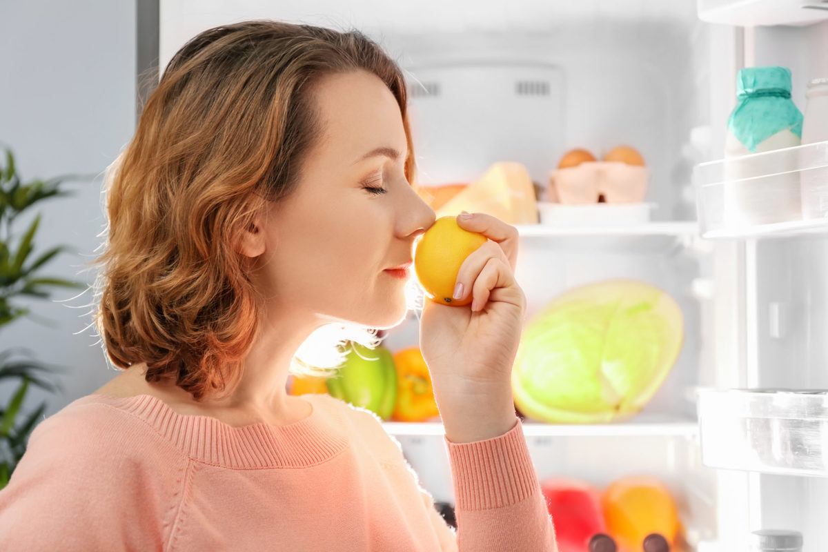 A woman smells a lemon from her refrigerator. Limonene is a terpene that creates the unique smell of citrus fruits.