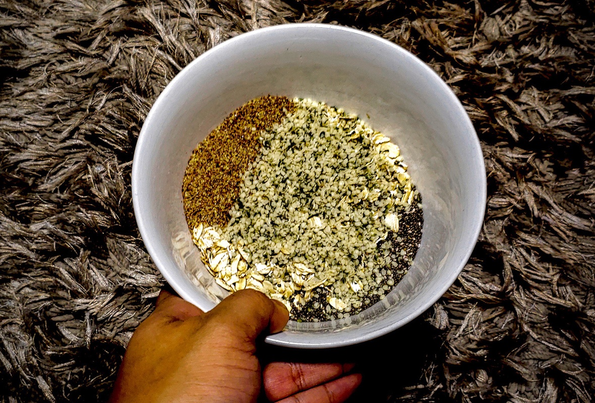 Oats, hemp seeds, chia seeds, and flax seeds are mixed in a microwave-safe bowl. It takes just minutes to mix all the ingredients and cook our "Ultimate Hemp Oatmeal" recipe.