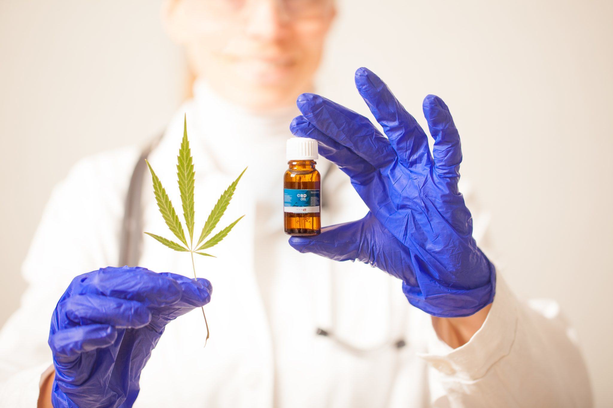 A gloved scientist with a vial of CBD and a hemp leaf. Preliminary research supports further investigation into using CBD to treat bipolar affective disorder.