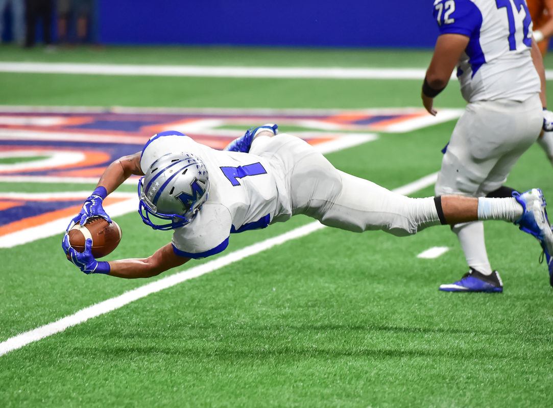A professional football player dives for the end zone while holding a football, dressed in a helmet and other typical gear. Despite other sports organizations beginning to soften their position on cannabis, NFL athletes are still barred from using any form of cannabis and avoid CBD.