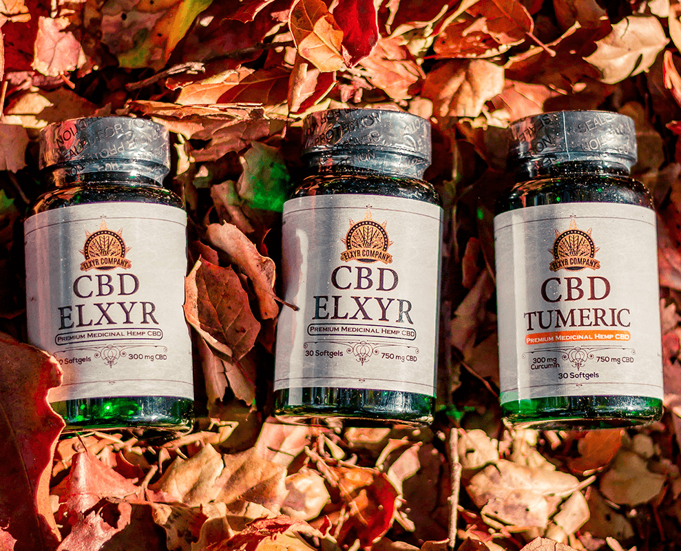 Elxyr CBD Softgels in two strengths, both with and without turmeric. The bottles are posed against a natural, leafy background.