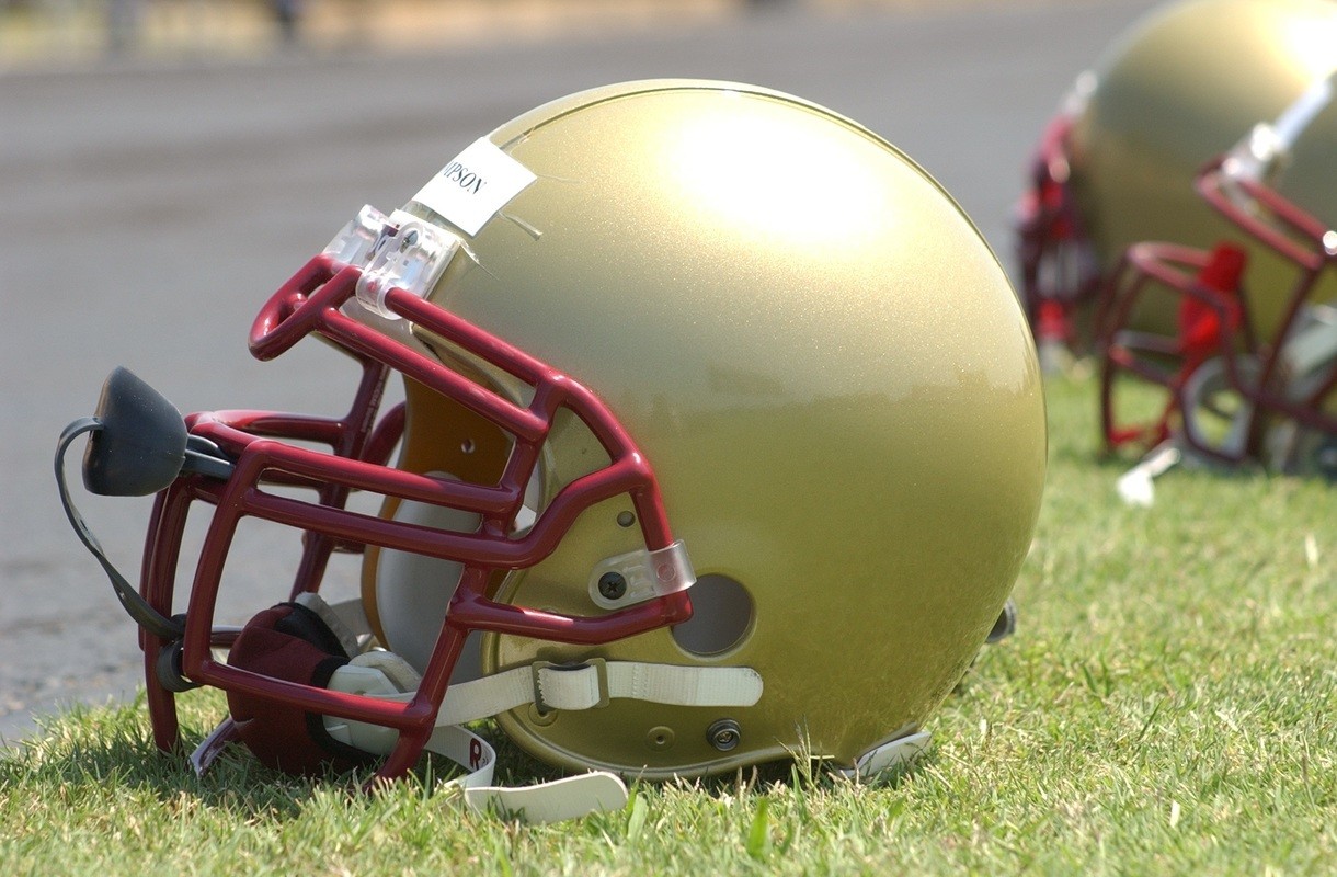 Football helmets sit on a football field. Despite advances in safety gear, football players still face repeated injuries and treatment can leave them addicted to painkillers.