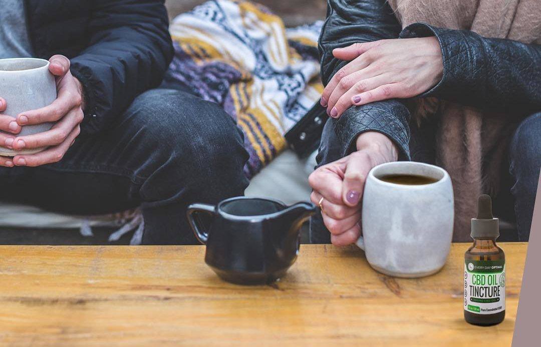 We wanted to compare CBD vs. CBG to help people understand how these two potent cannabinoids are similar, yet different. Photo: Two people in warm clothes share mugs of tea, while a teapot and a bottle of Every Day Optimal rests nearby.