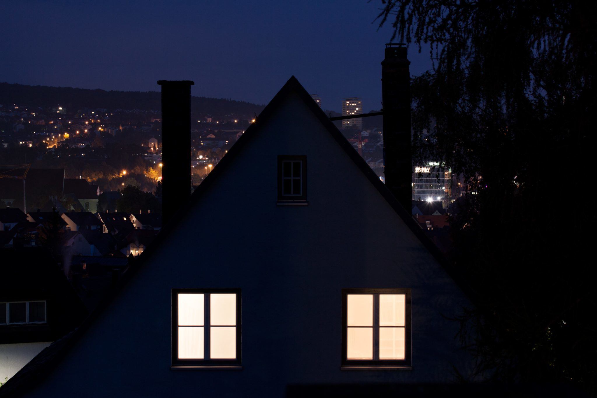 During insomnia, the brain goes into flight-or-fight mode, leaving would-be sleepers too alert to drift off. Photo: A house with its lights on at the top floor, with a night time city in the background.