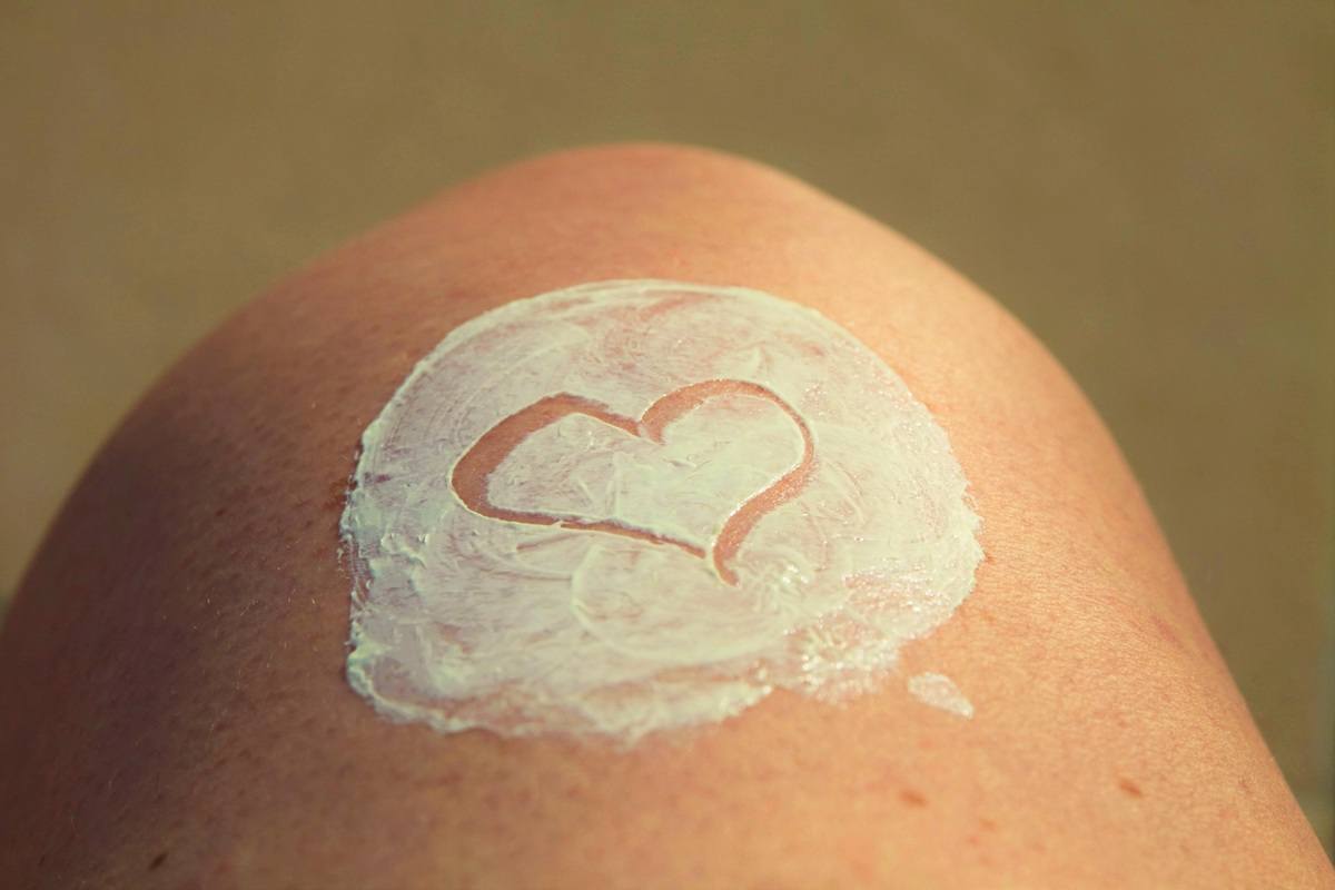 A person's knee with topical lotion applied in a heart shape.