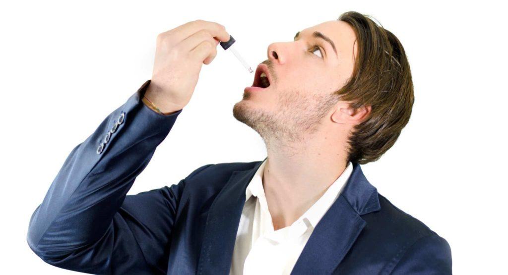 CBD tinctures are the most common type of CBD product. Photo: A person in a suit jacket and button down formal shirt takes a CBD tincture from a dropper.