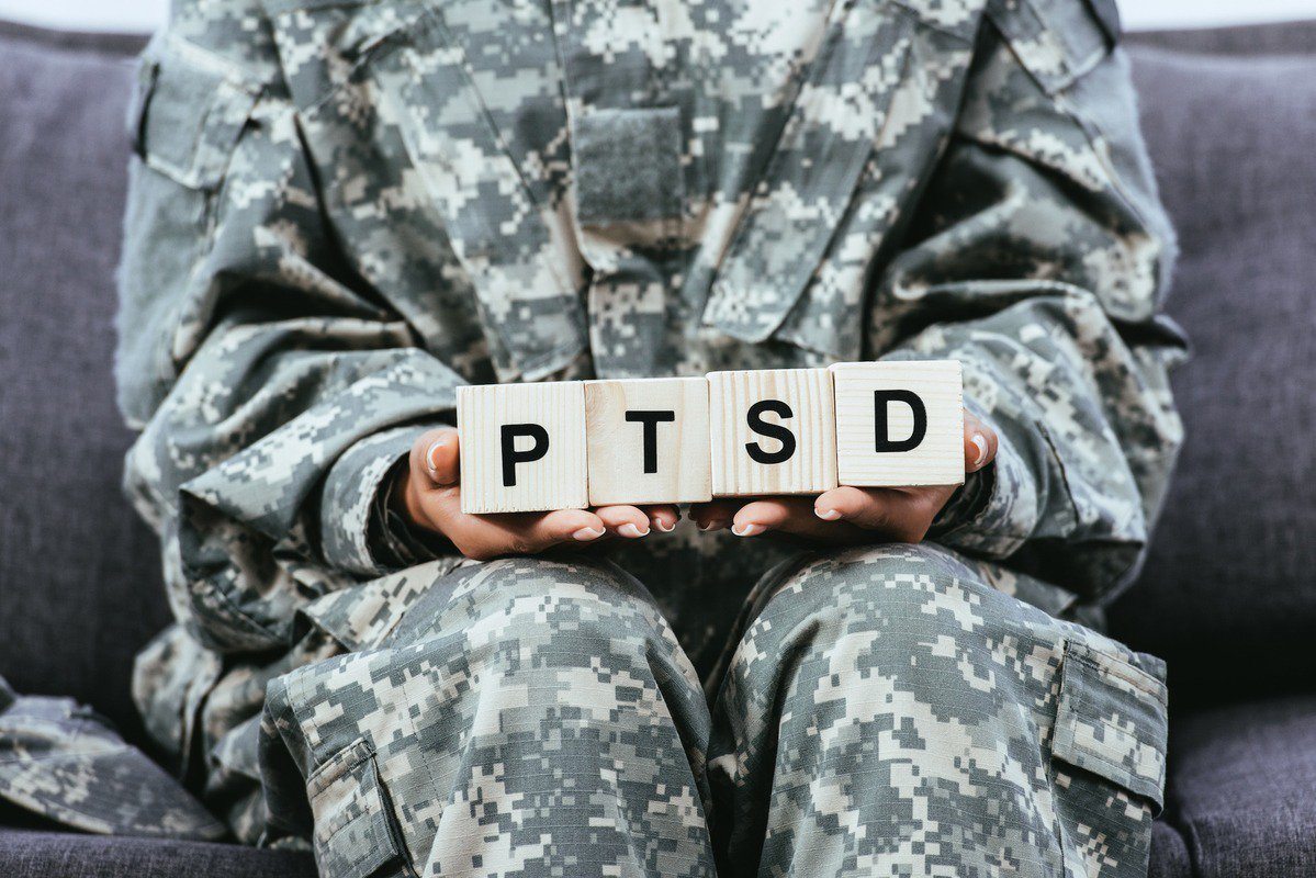 Using CBD for PTSD can ease some of this complex condition's most troubling symptoms. Photo: Cropped shot of female soldier in military uniform sitting on sofa and holding wooden cubes that spell PTSD.