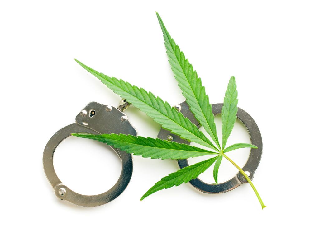 Despite the 2018 Farm Bill, some people still get arrested over hemp. Photo: A hemp leaf with a pair of handcuffs.