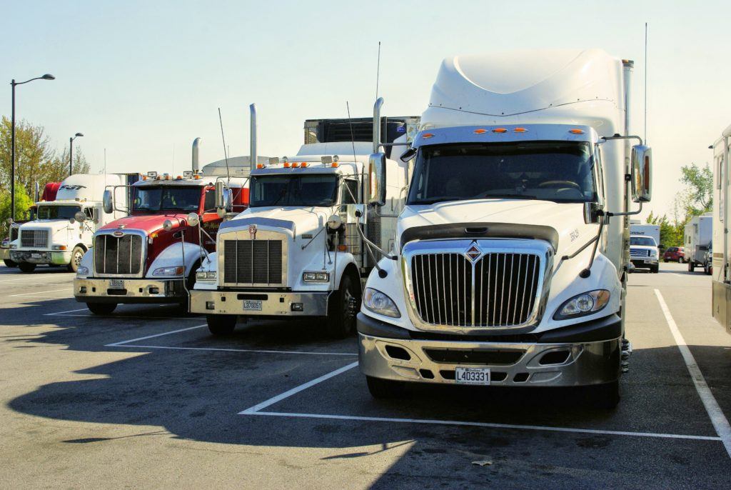 Recent arrests of truckers with hemp in Idaho and elsewhere are a troubling sign of the confusing legal landscape around hemp. Photo: A row of tractor trailor trucks lined up in a parking lot.