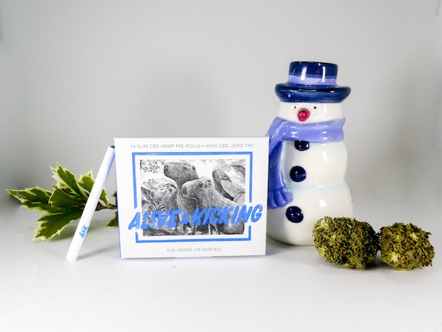 Alive & Kicking Slim CBD Pre-Rolls posed with buds of hemp flower and a ceramic snowman.