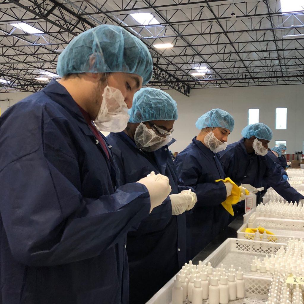 With a white label CBD business, your supplier creates products tailored to your needs and you focus on marketing them to your customers. Photo: An assembly line of workers in protective gear carefully creates white label CBD products.