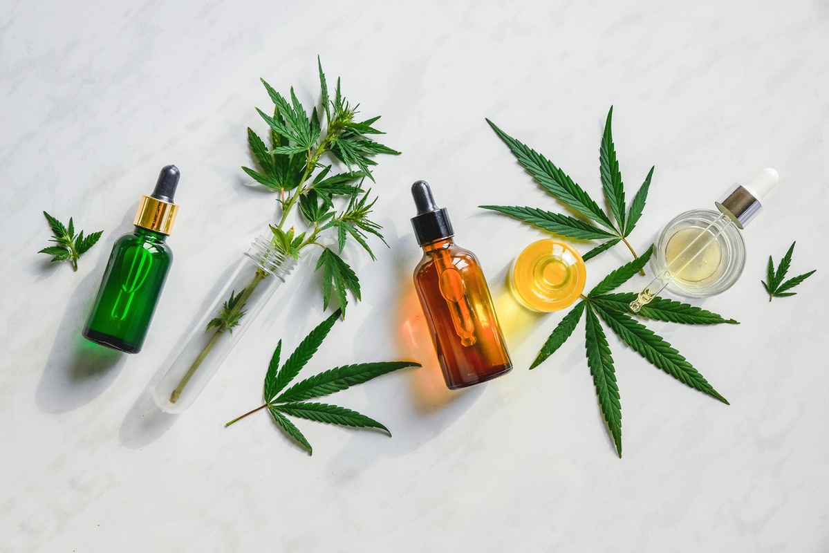 Our guide to choosing high quality CBD oil will make your next purchase easier. Photo: Generic bottles and other containers of CBD oil along with decorative hemp leave.