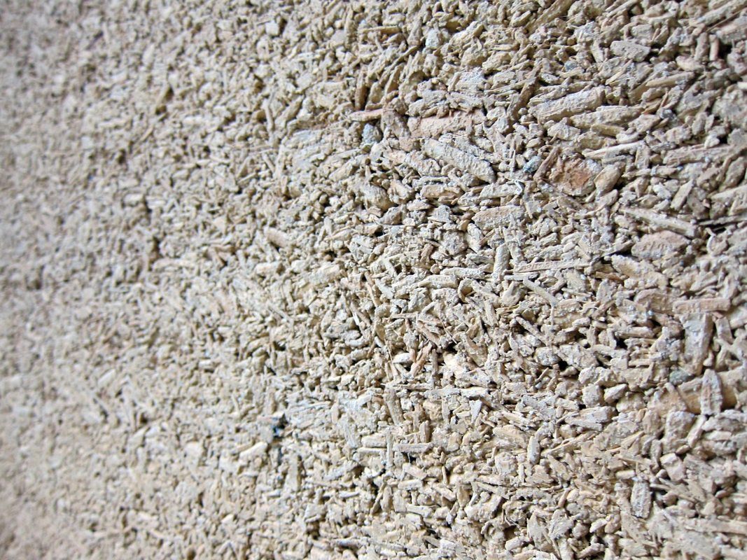 A close up of the surface of a hempcrete wall. The woody texture of the hemp shivs is still visible in the finished product, which many homebuilders find appealing.