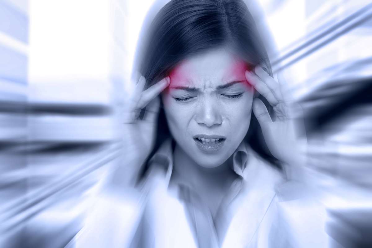 A woman clutches her head in pain, as if suffering from a migraine. Clinical endocannabinoid deficiency could be a root cause of migraine and other diverse conditions.