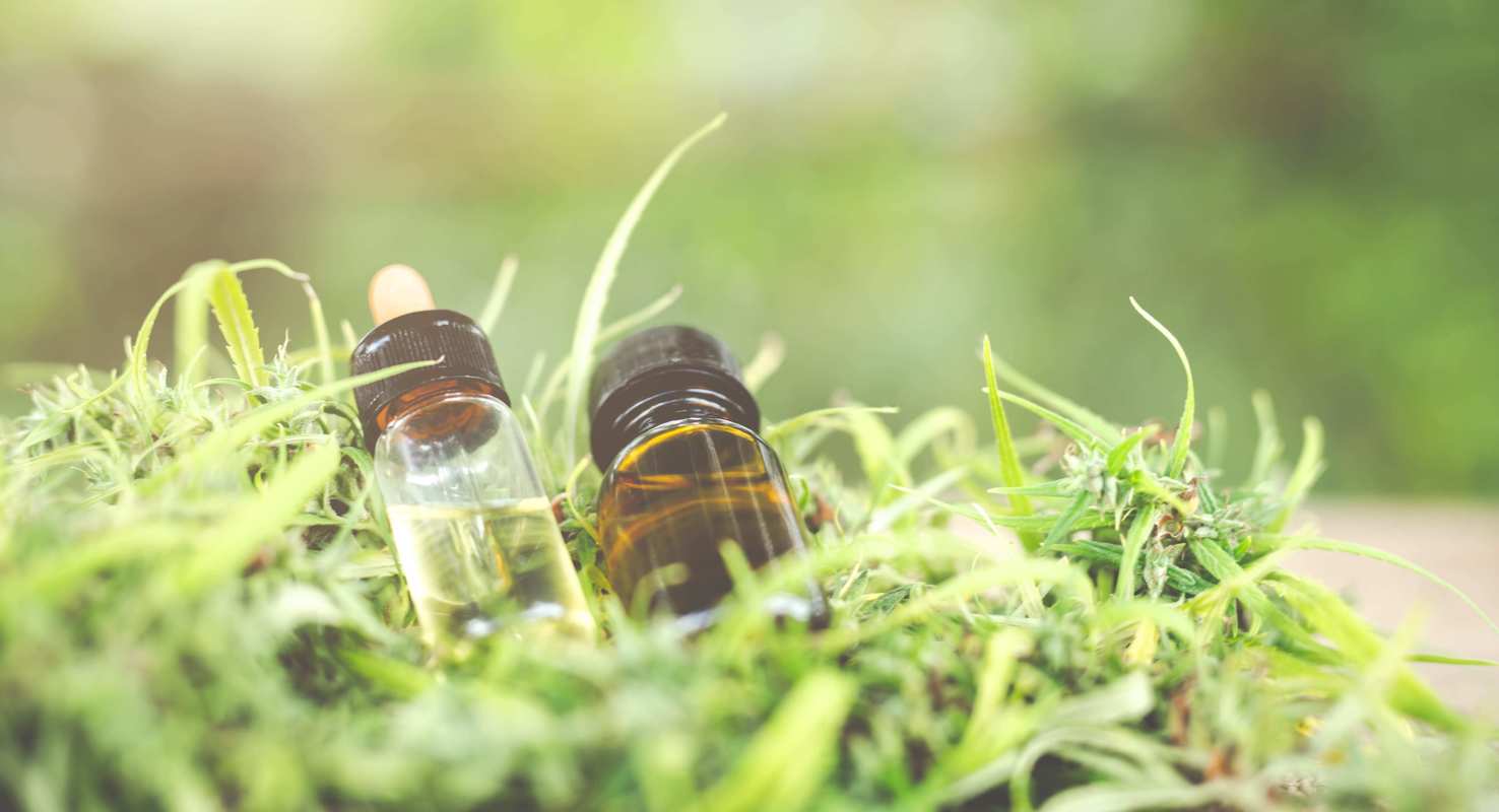 Two different colored vials of hemp extract sit on a bed of hemp leaves. Full spectrum CBD contains more cannabinoids and other natural compounds, while CBD isolate may be better for people who need a strong dose of just cannabidiol.