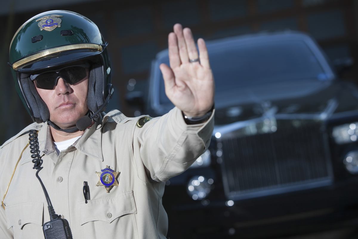 A highway patrol officer holds his palm out while making a road side stop. Oklahoma police seized 18,000 pounds of hemp and charged four people with felony drug trafficking crimes for transporting legal hemp.