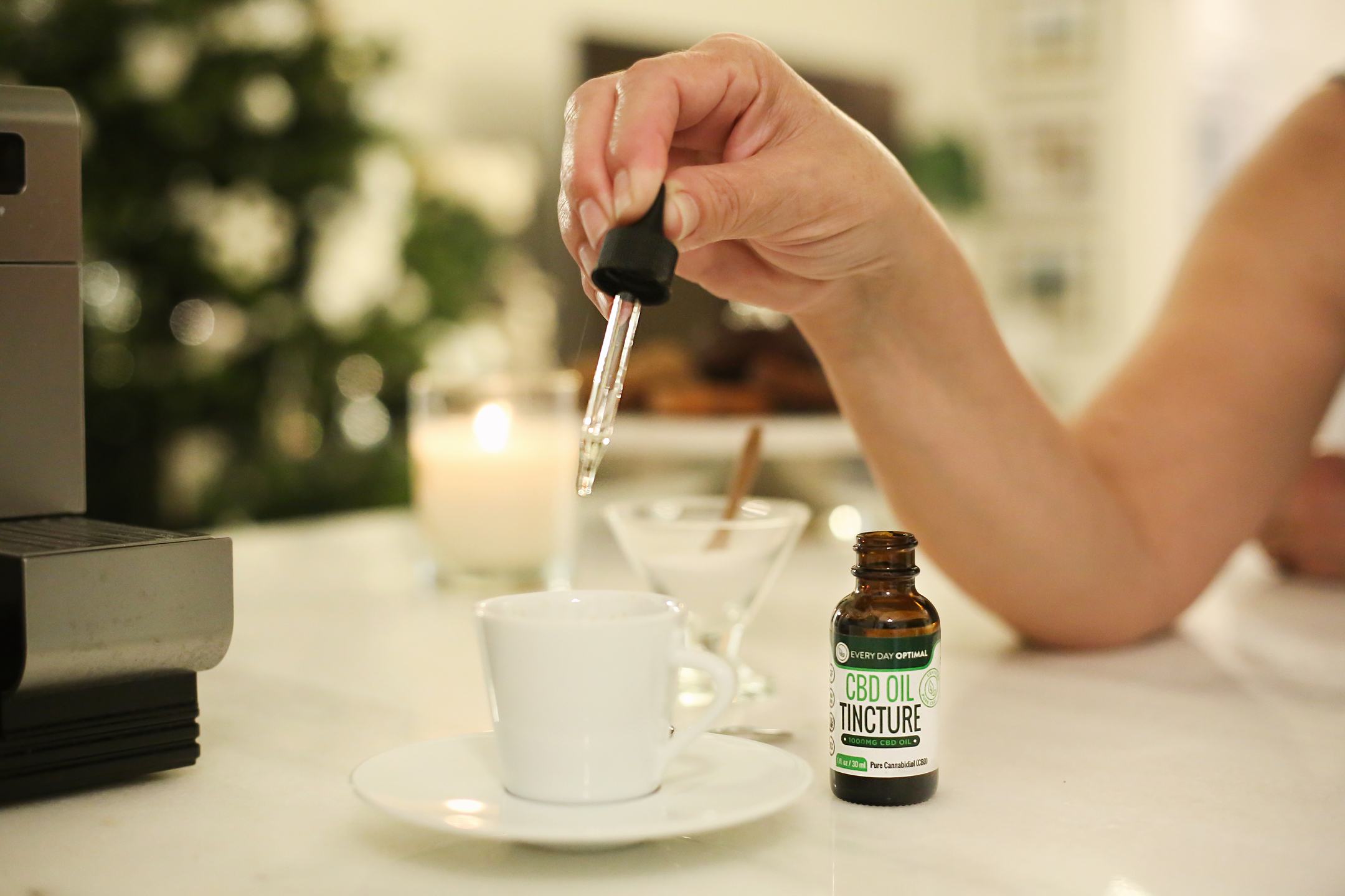 In this article we compare CBD vs. CBN for their different health benefits. A person drops a dropperful of CBD oil from a bottle of Every Day Optimal into a cup of espresso.