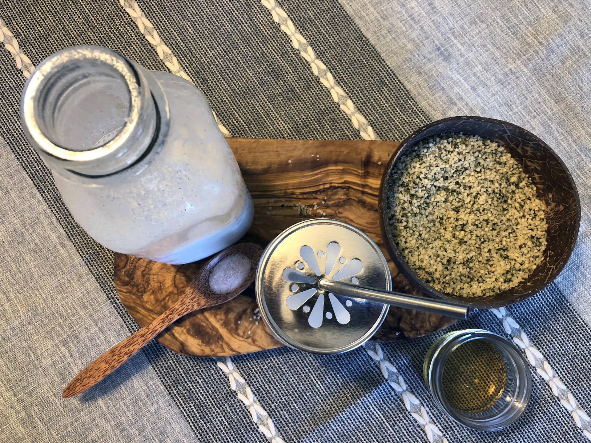 A jar of our DIY hemp milk sits near ingredients for making it, including hemp hearts and salt.