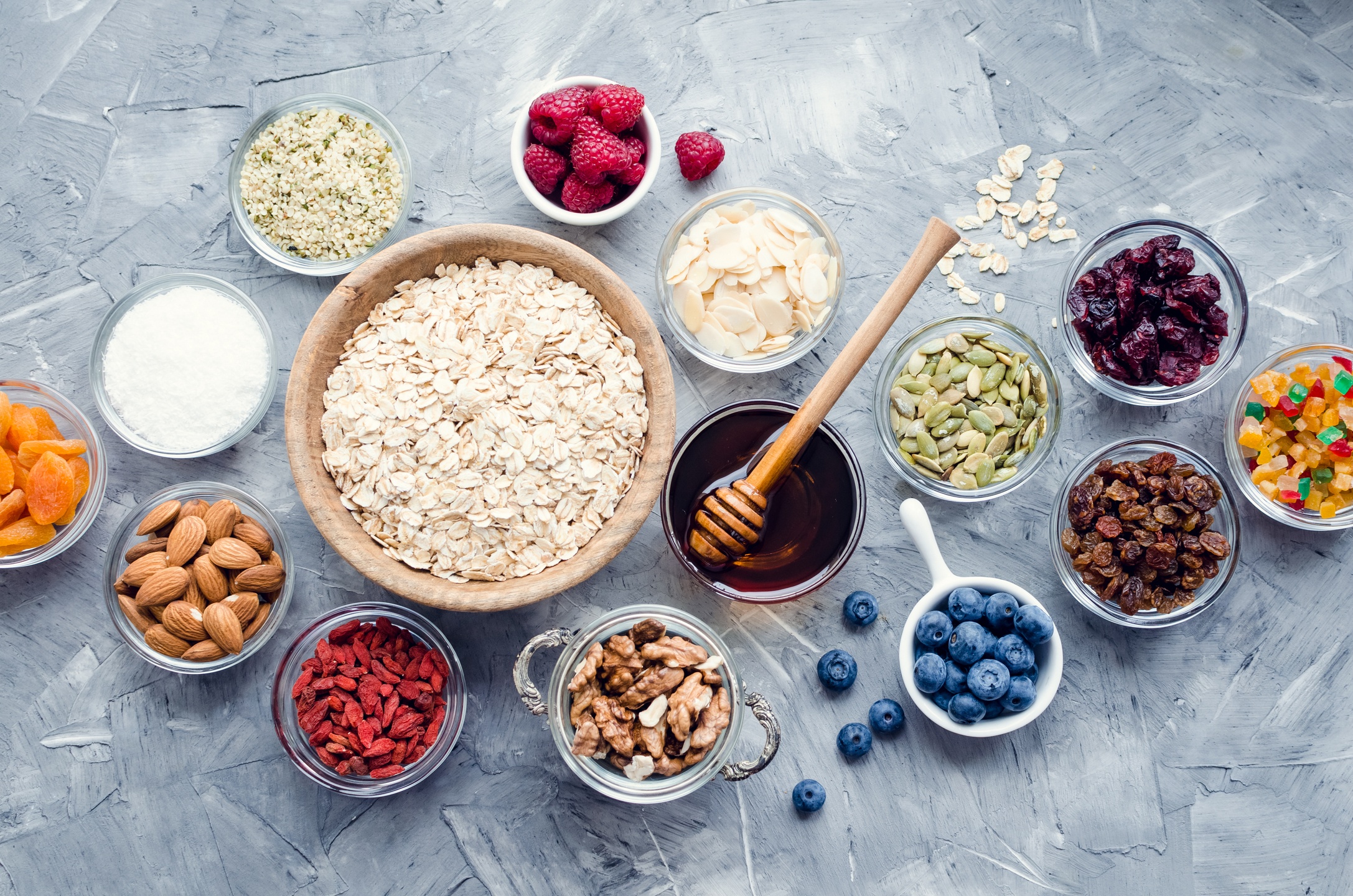Delicious, nutritious, and easy to customize, our hemp granola recipe will be your new easy breakfast snack. Photo: Various granola ingredients in bowls including oats, hemp hearts, honey, nuts, and berries.