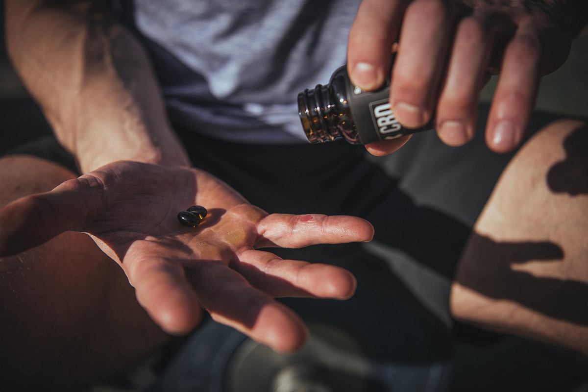 Photo: An athlete holds CBD capsules in their hand.