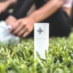 Canvas 1839 Relief Oil impressed us by offering pure, unadulterated CBD oil relief. Photo: A cardboard tube containing Canvas 1839 Relief Oil rests in the grass outside, with a person sitting in the background behind them.