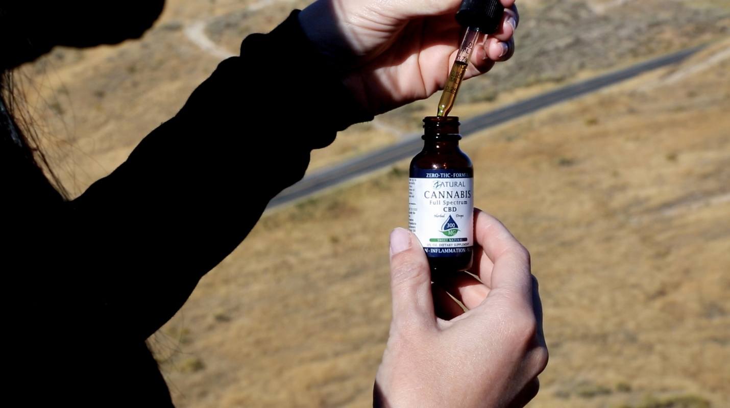 Almost anyone can use CBD to help feel more in balance. Photo: A person takes a dropper full of Zatural CBD out of the bottle using the dropper top.