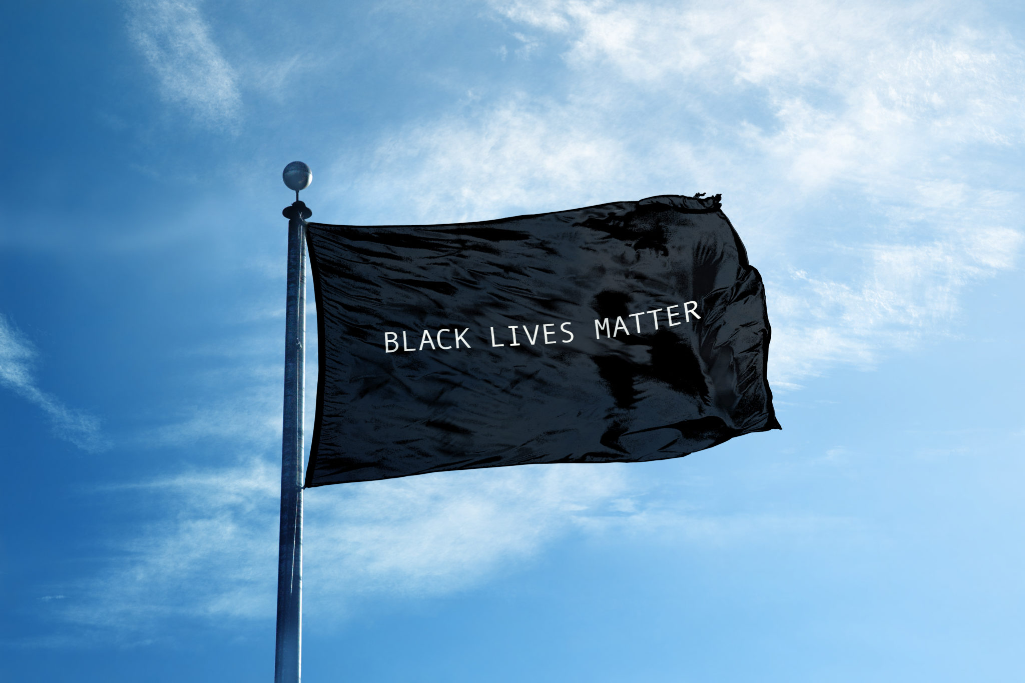The hemp industry needs to take a stand for black lives. Photo: A Black Lives Matter flag on a flag pole against a partly cloudy blue sky.