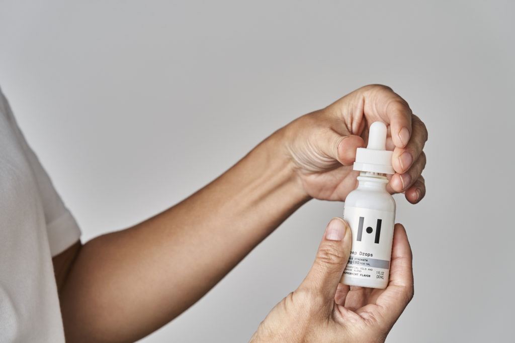 A person holds a bottle of Healist Naturals Sleep Drops in the double strength peppermint flavor..