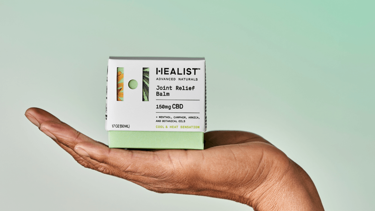 Photo: A person holds the Healist Naturals Joint Relief Balm box in their open palm.